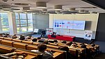 grupa ludzi siedzi w auli i słucha mężczyzny