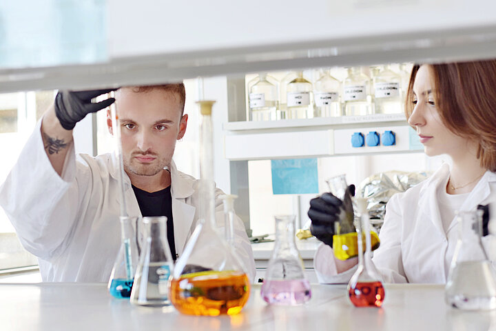 mężczyzna i kobieta ubrani w fartuchy pracują w laboratorium