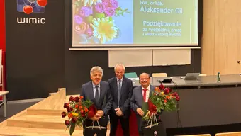 trzech mężczyzn ubranych galowo stoi obok siebie w rękach trzymają kwiaty