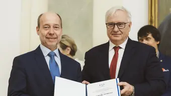 dwóch mężczyzn ubranych w garnitury pozuje z dokumentem