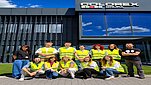 grupa młodych osób ubranych w kamizelki odblaskowe stoi obok siebie oraz kuca, pozują do wspólnego zdjęcia
