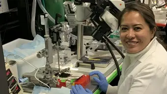 kobieta w fartuchu siedzi przy stole laboratoryjnym