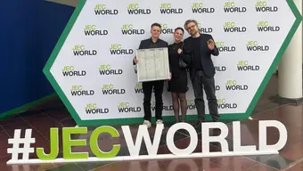 trzy osoby stoją obok siebie w tle ścianka reklamowa