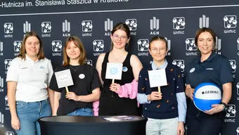 kilka osob ubranych nieformalnie stoi obok siebie w tle ścianka reklamowa