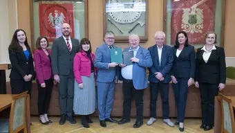 grupka osób stoi obok siebie ubrani elegancko